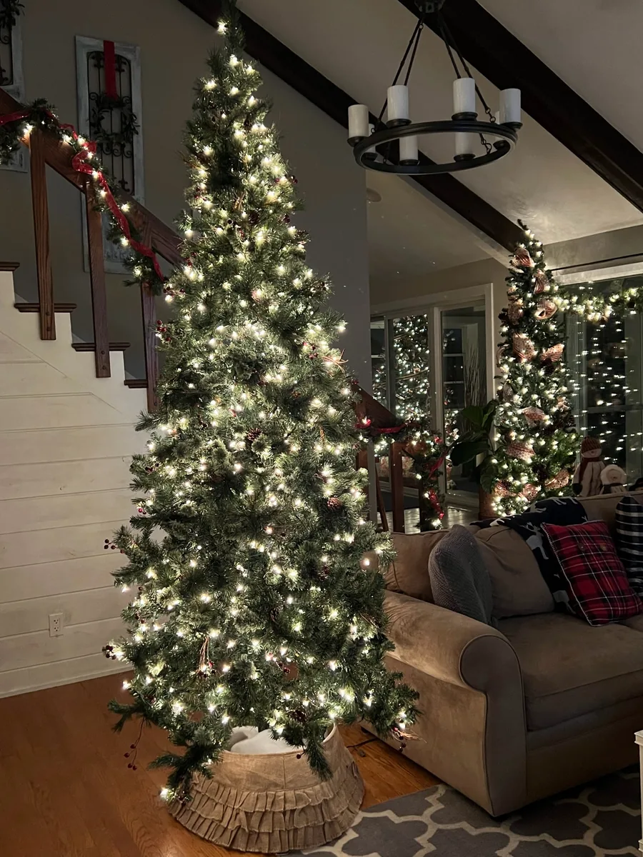 A softly lit Christmas tree and garland frame a living-room stairway.